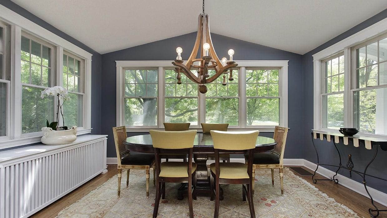 A dining room with single hung windows and a table and chairs.