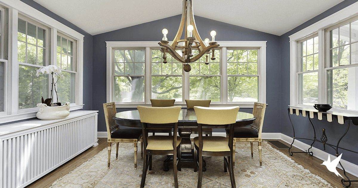 A dining room with a table and chairs, featuring single hung windows.