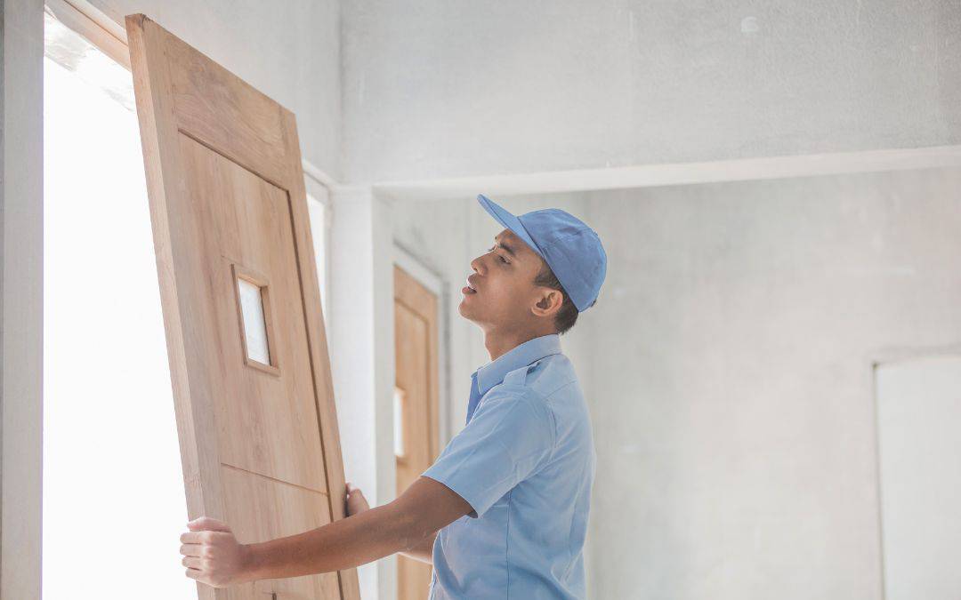 hiring-professional-to-install-doors-will-improve-energy-efficiency - Worker installing a wooden door