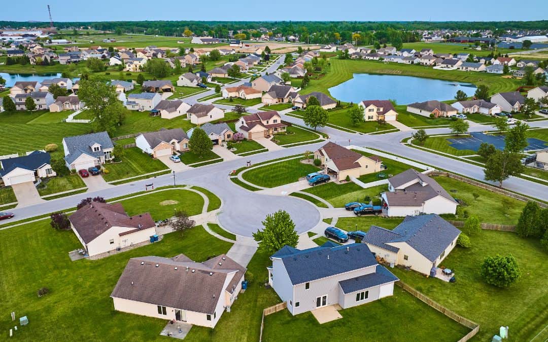tour-your-neighbourhood-for-inspiration-for-your-home-exterior-makeover - Aerial view of a suburban neighborhood with neat houses, curving streets, and multiple ponds on a sunny day.